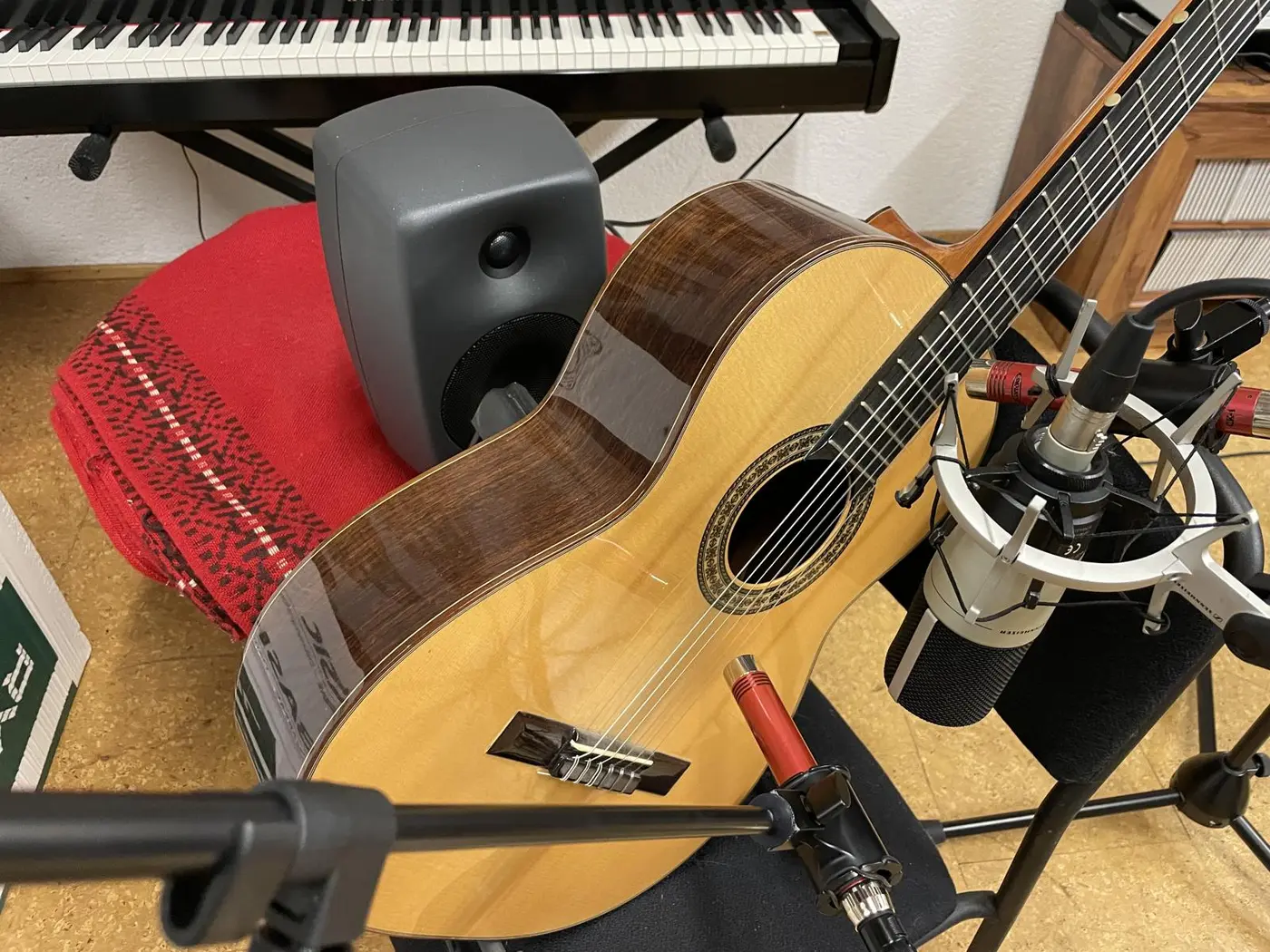 Re-amping an acoustic guitar: studio monitor behind a classical guitar, large- and small-diaphragm microphones in front